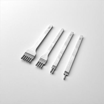 Set of four metal leather stitching punches on a light grey background