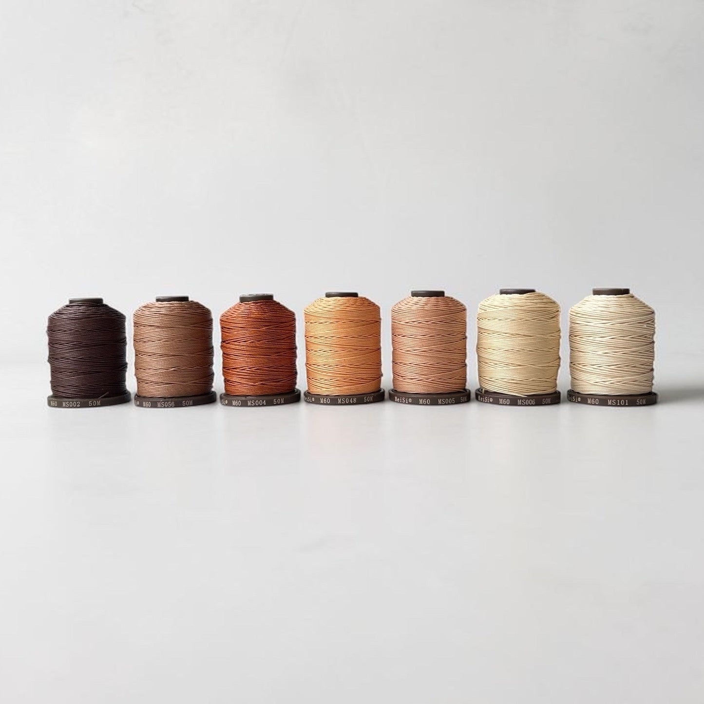 Set of six spools of thread in various colors on a white background