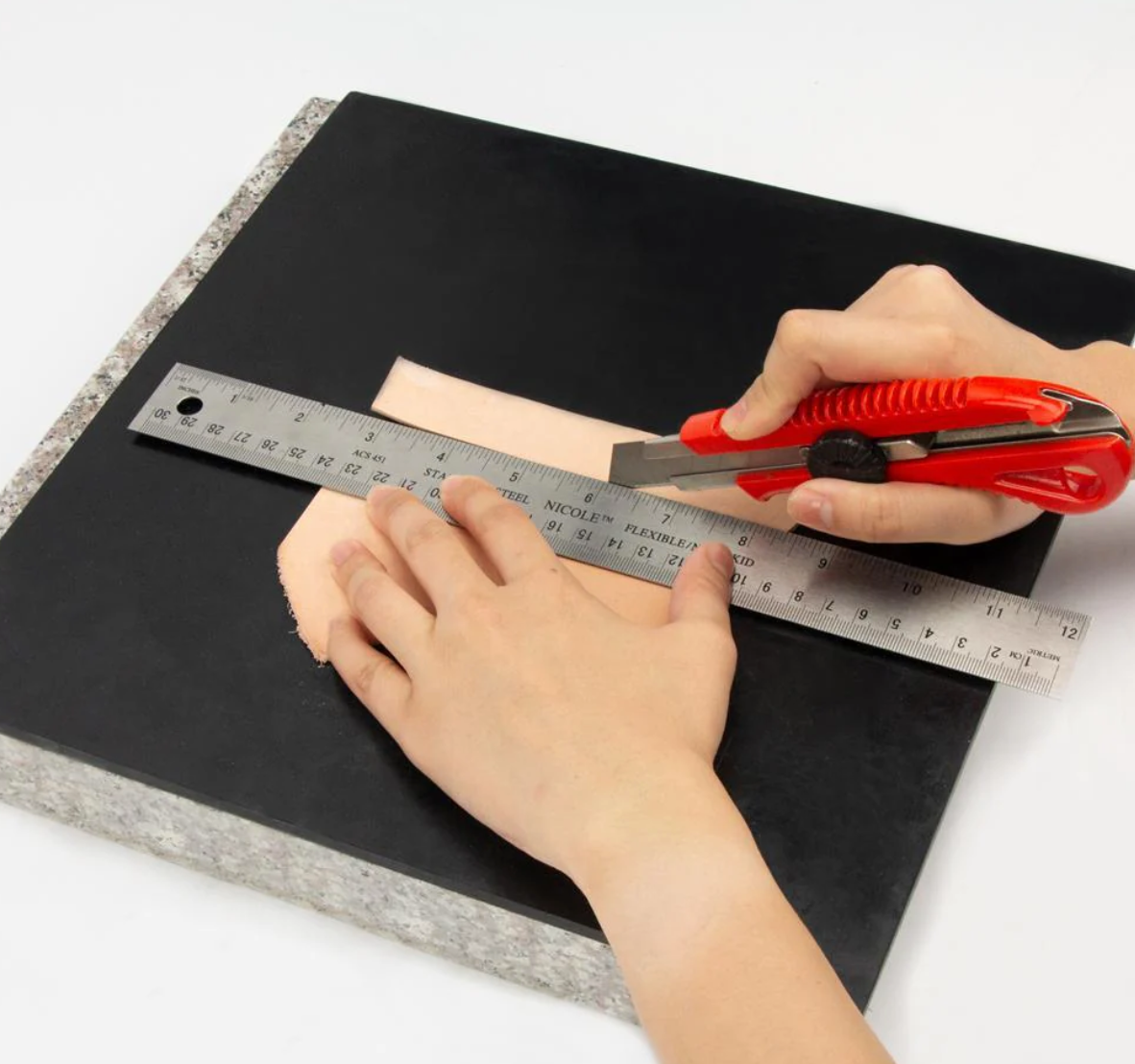 Person cutting a piece of leather with a knife on a black poundo board for leathercraft 