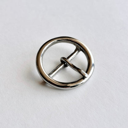 Silver metal circular buckle with a central bar on a light gray background