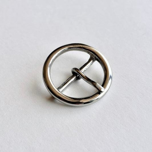 Silver metal circular buckle with a central bar on a light gray background