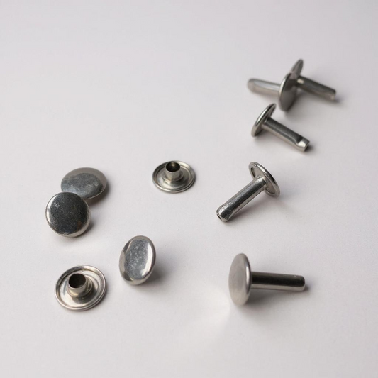 Silver Double Capped leather rivets on a grey background