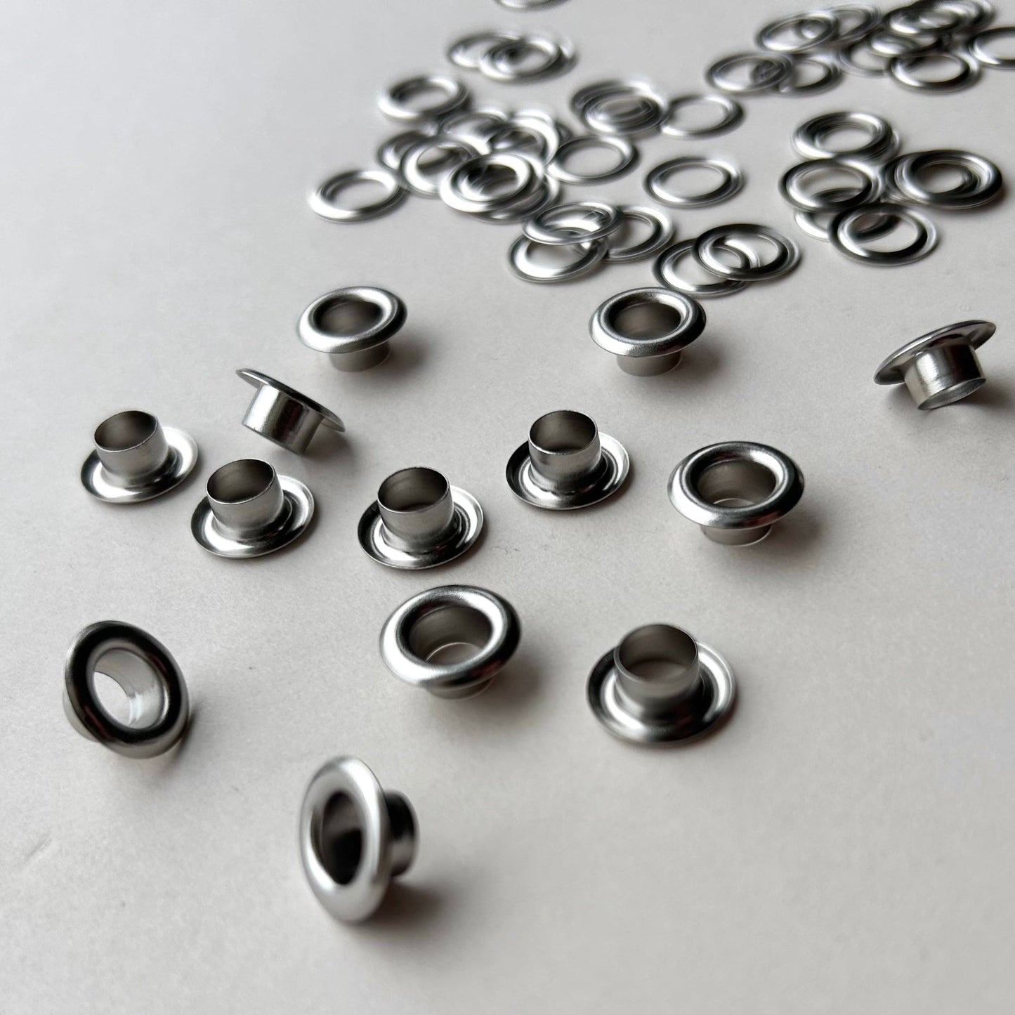 Metal eyelets scattered on a light gray background