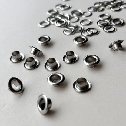 Metal eyelets scattered on a light gray background