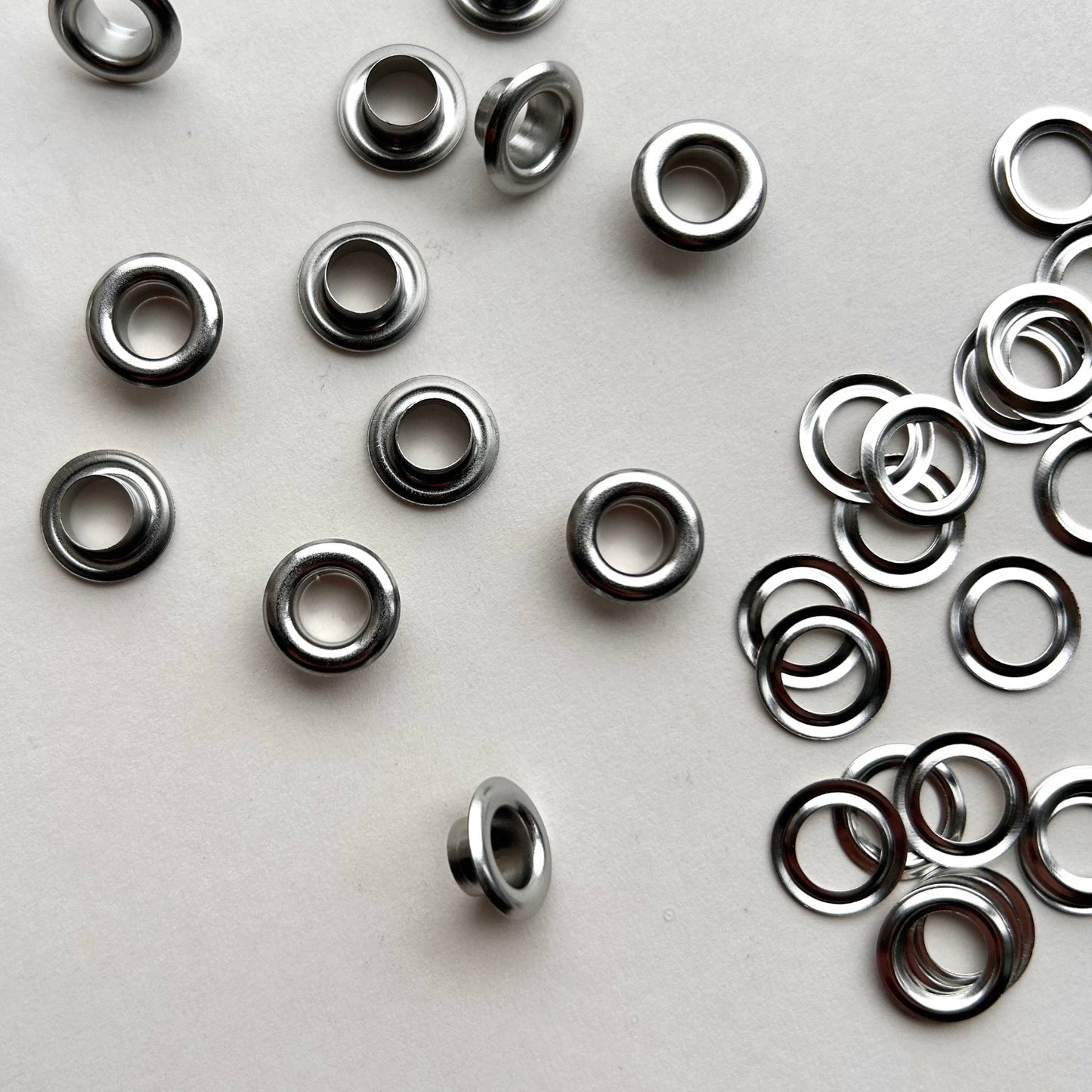 Metal eyelets scattered on a white background