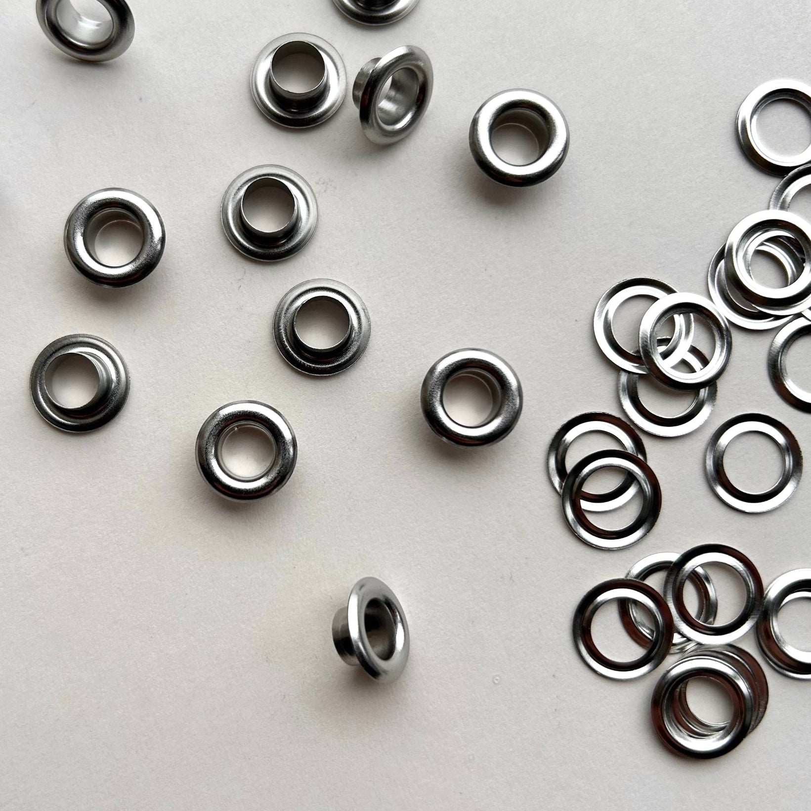 Metal eyelets scattered on a white background