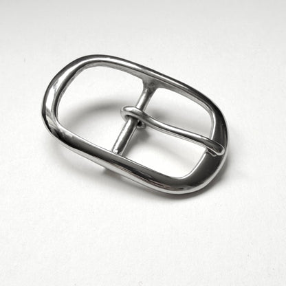 A polished silver metal belt buckle with a rounded rectangular shape and a single prong, shown on a light gray textured background.