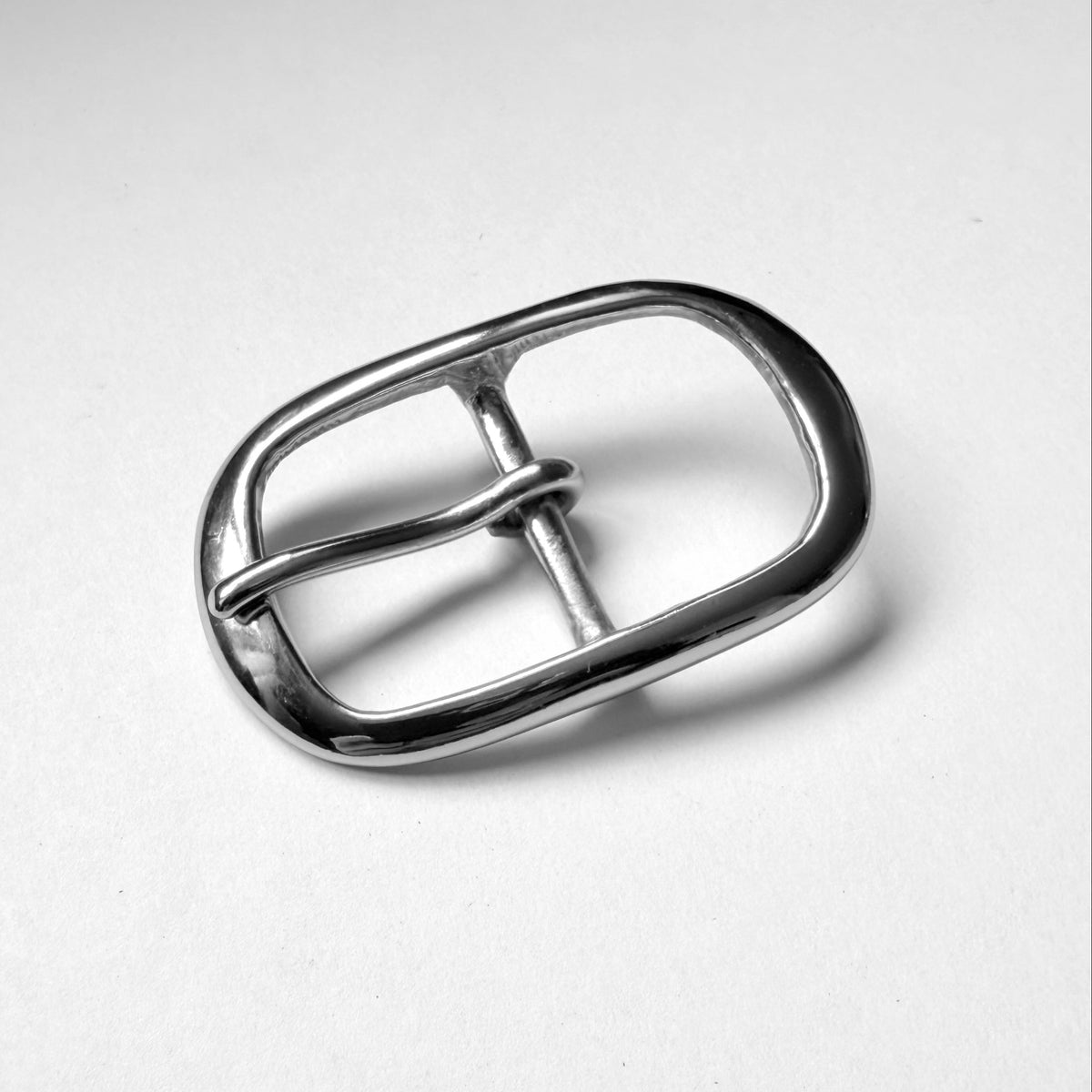 A polished silver metal belt buckle with a rounded rectangular shape and a single prong, photographed on a clean white background.