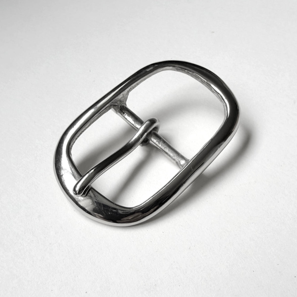 A polished silver metal buckle with a rounded, elongated oval shape, photographed on a plain white surface.