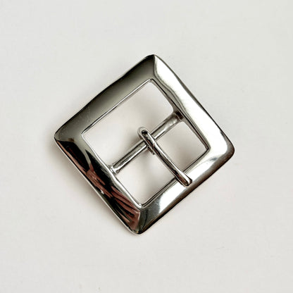 A polished silver-tone metal square buckle with a two-prong closure, photographed on a clean white background.