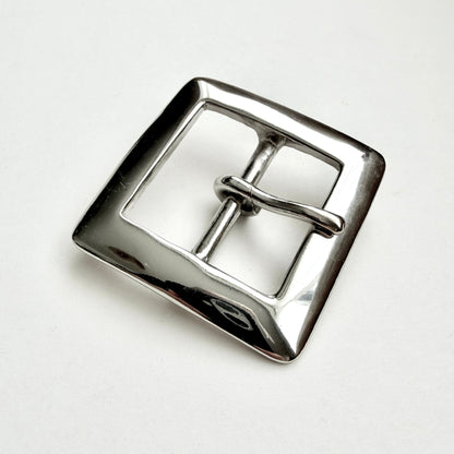 A polished silver-tone metal square buckle with a central bar and loop, photographed on a clean white background.