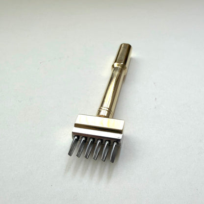 Gold coloured Sinabroks French Iron stitching punch on an off white background.