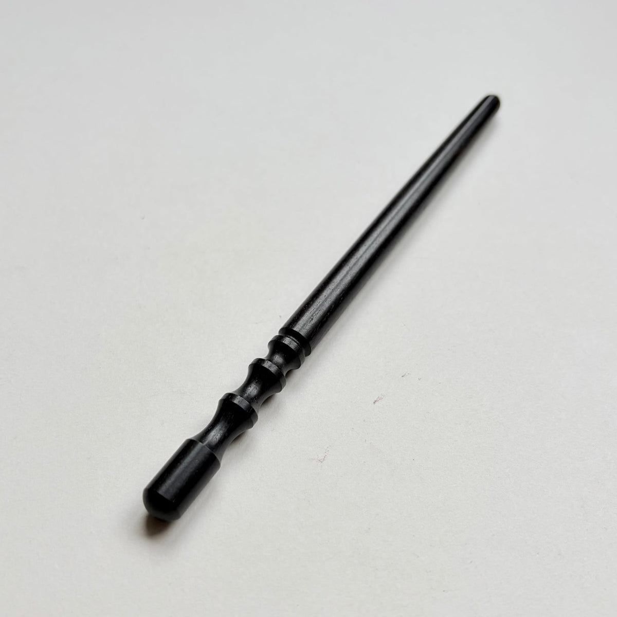 Narrow black wooden leather edge burnisher tool on a grey background