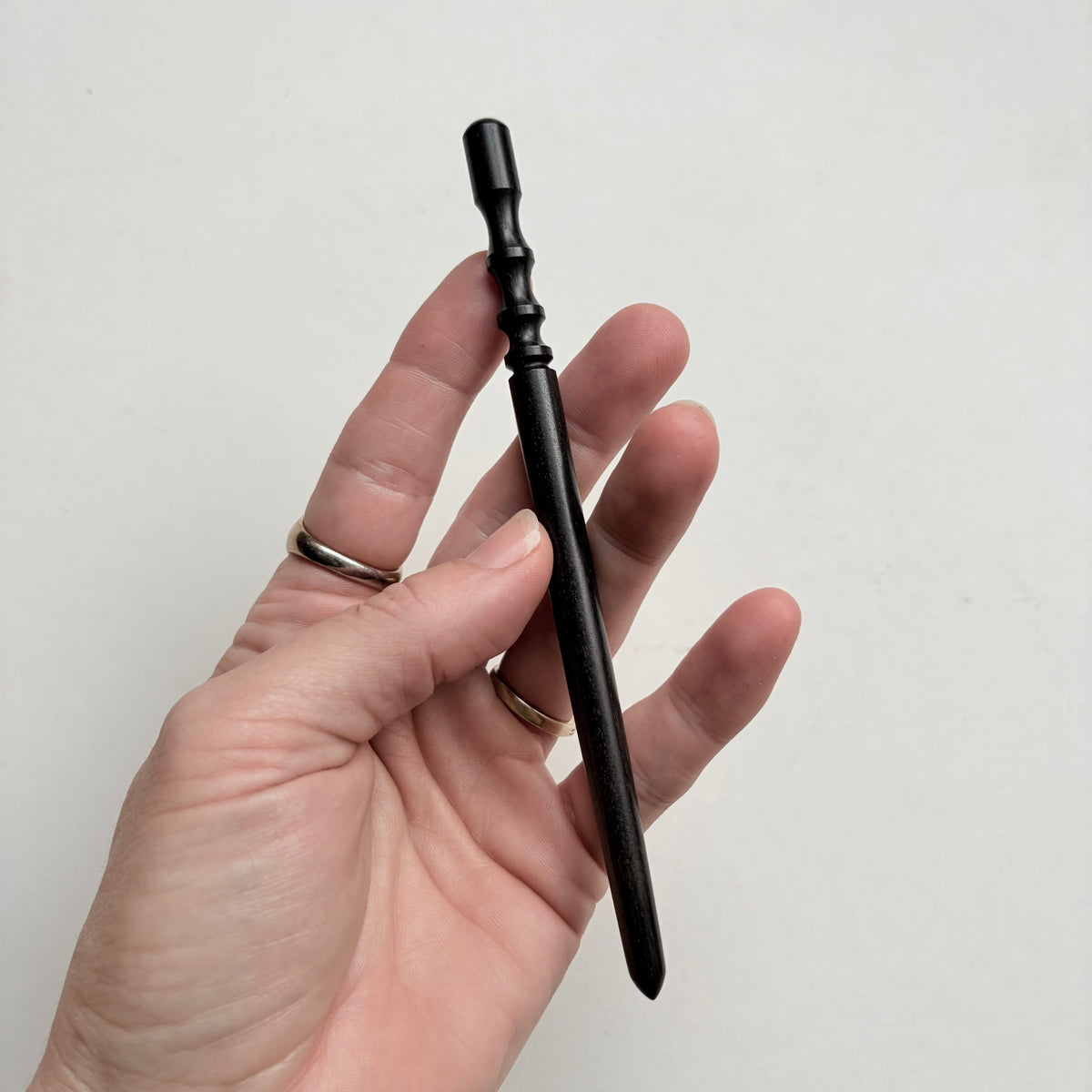 Narrow black wooden leather edge burnisher tool on a grey background