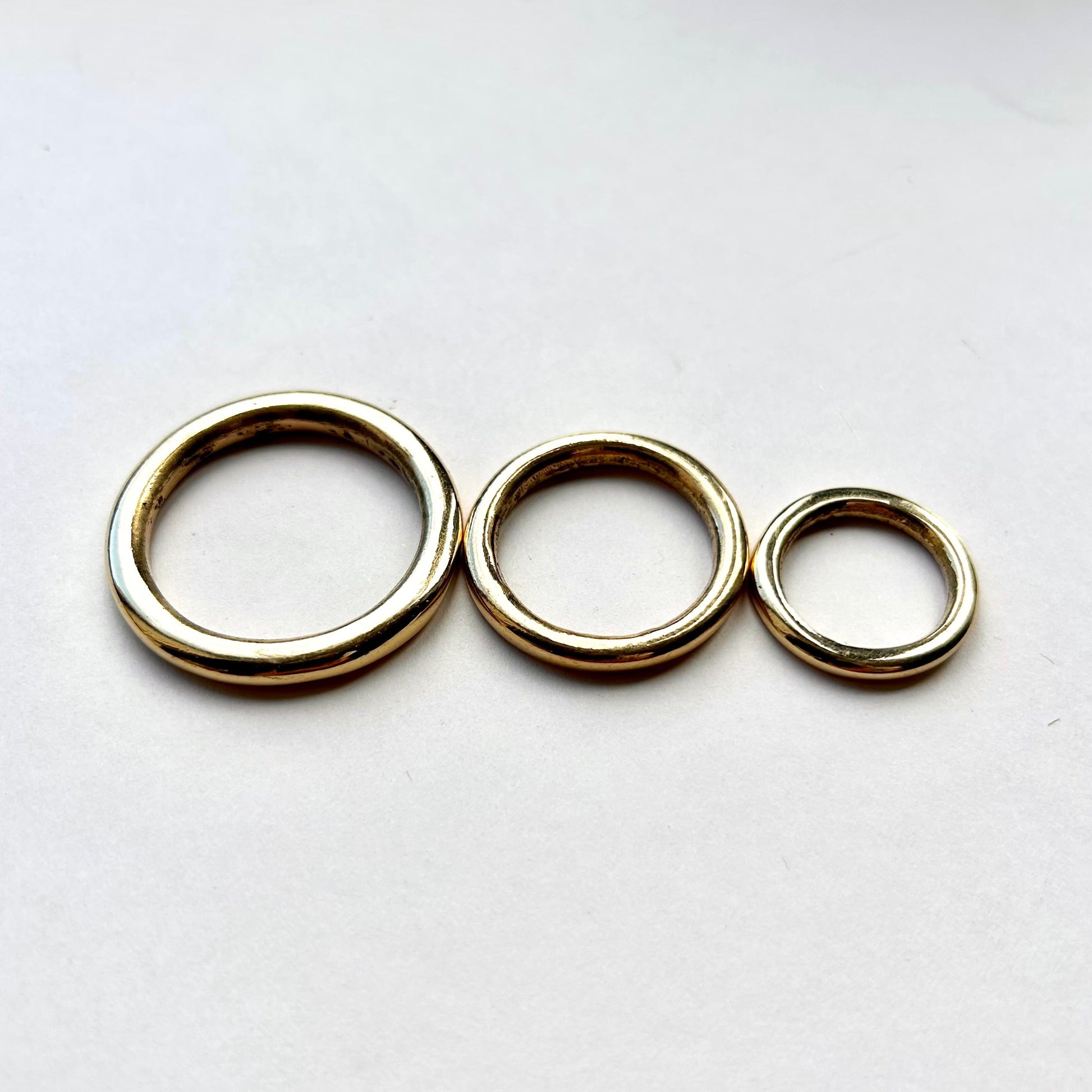 Three gold solid brass o rings for leathercraft on a white background