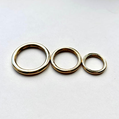 Three gold solid brass o rings for leathercraft on a white background