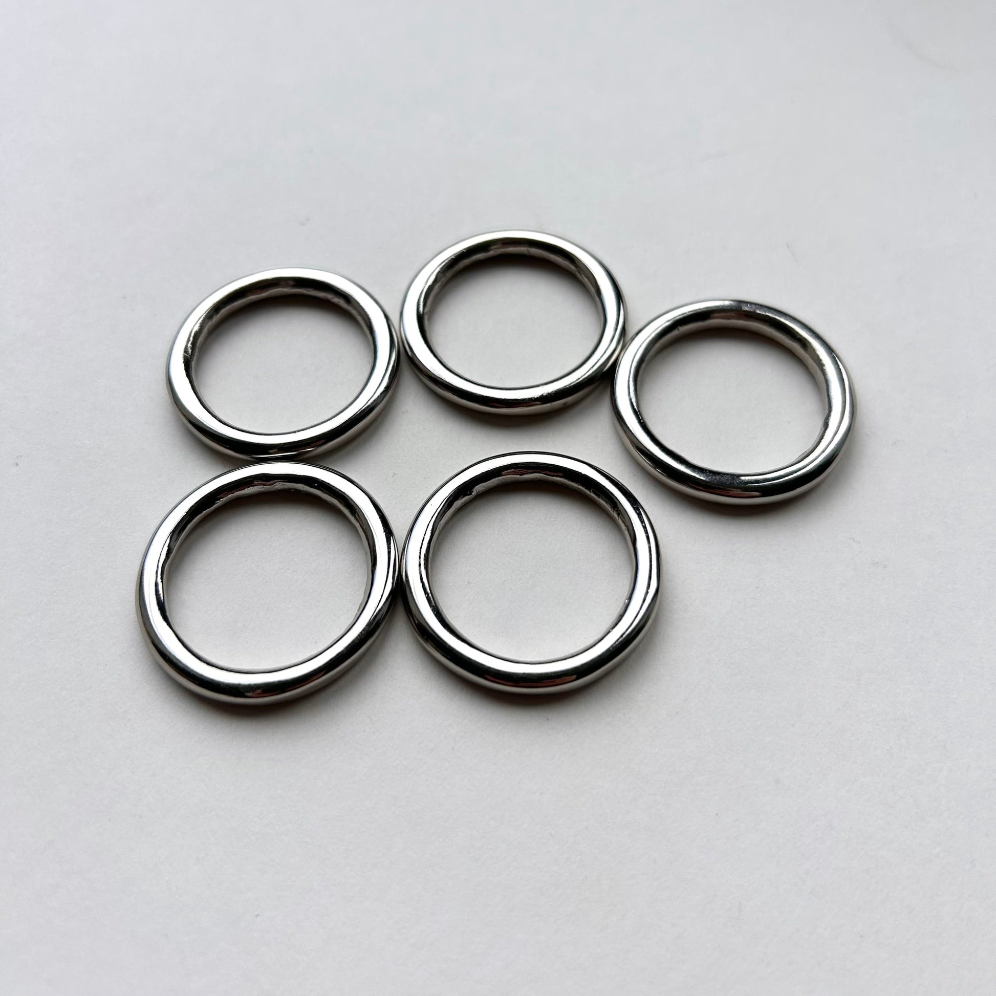 Five silver o rings on a light gray background