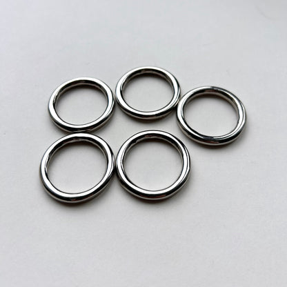 Five silver o rings on a light gray background