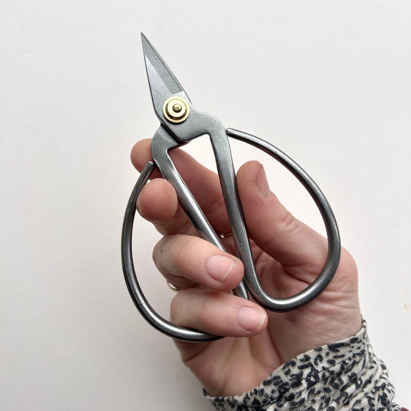 Hand holding a pair of silver scissors against a white background