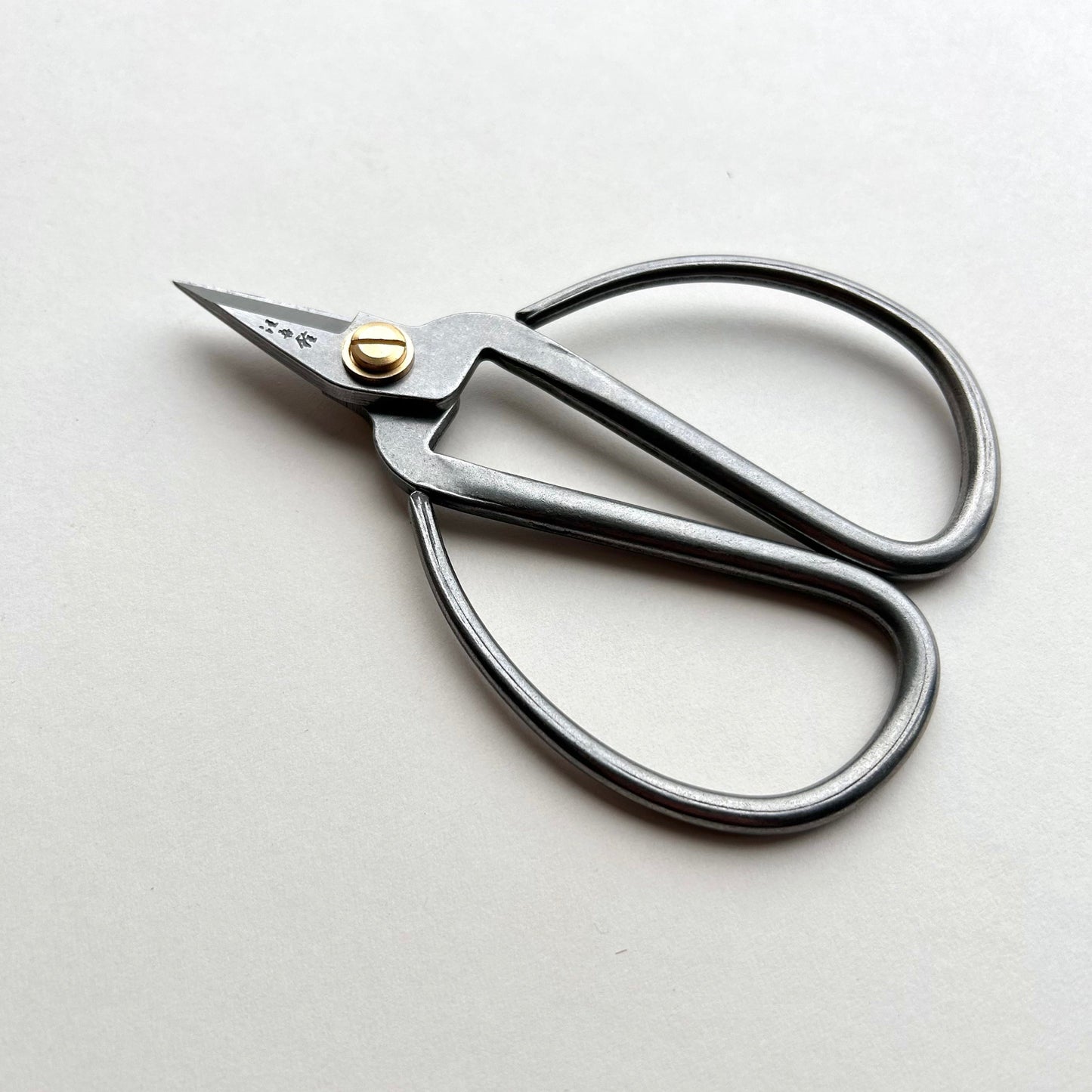 Pair of silver scissors with a gold heart-shaped pad on a light gray background
