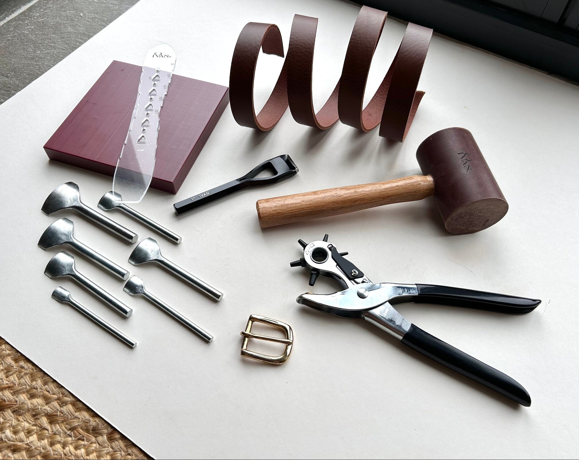 Set of tools and materials for leatherworking on a white surface