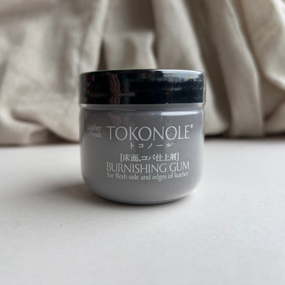 Jar of Tokonole burnishing gum in brown on a neutral background
