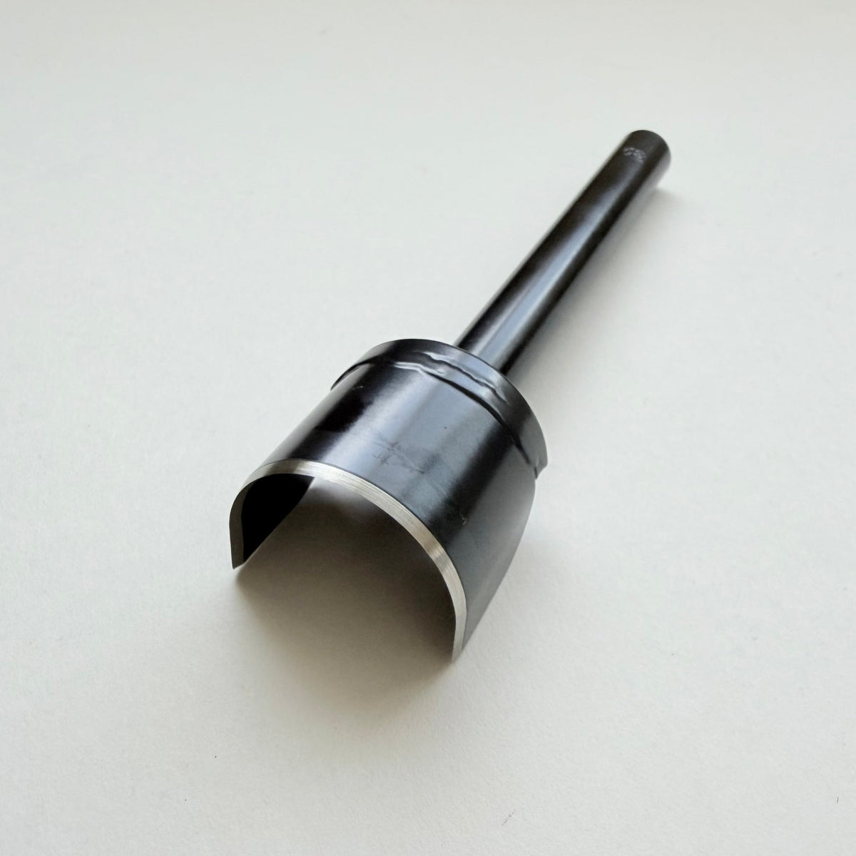 A black metal u shaped strap end punch with a silver steel cutting edge, shown on a plain light grey background.
