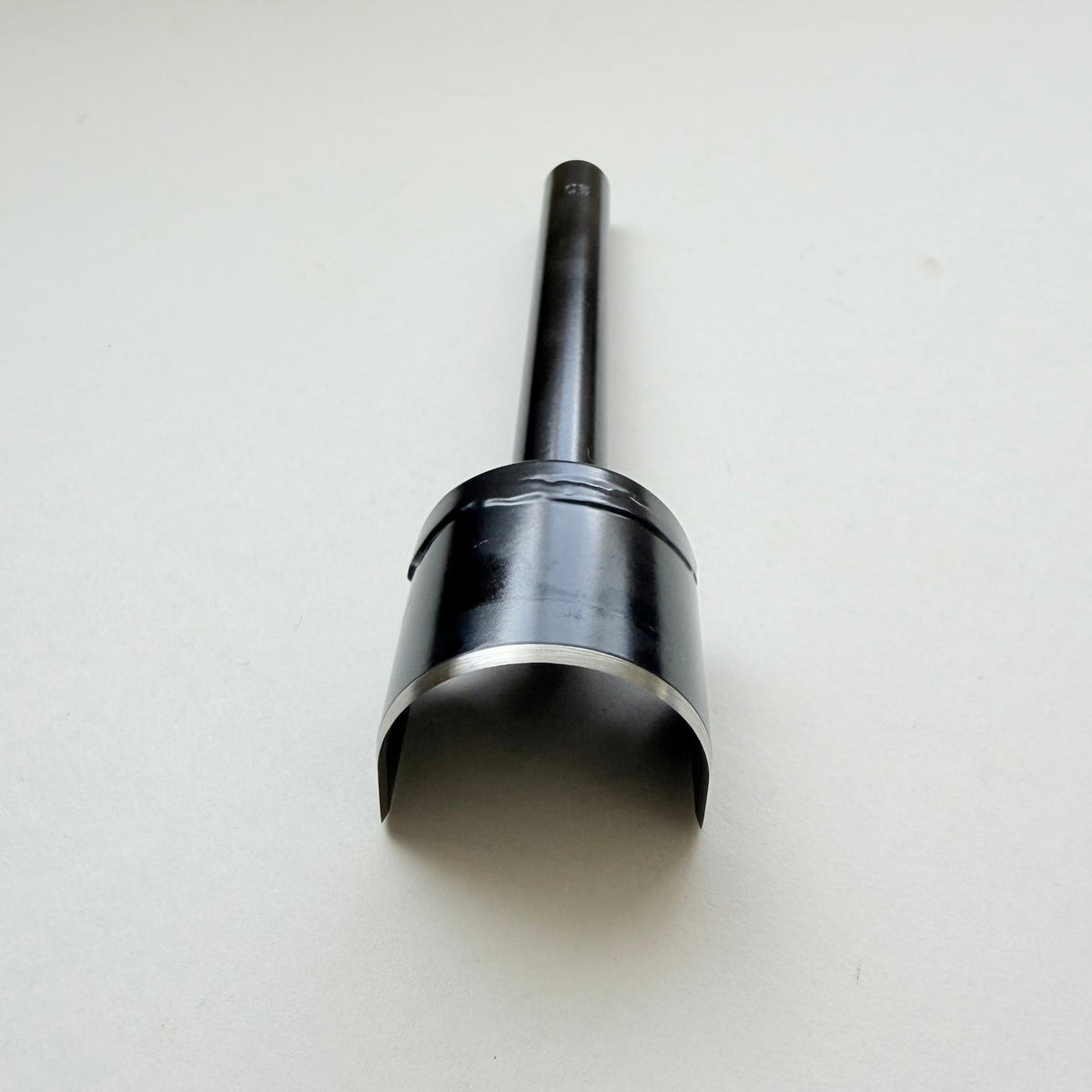 A black metal u shaped strap end punch with a silver steel cutting edge, shown on a plain light grey background.