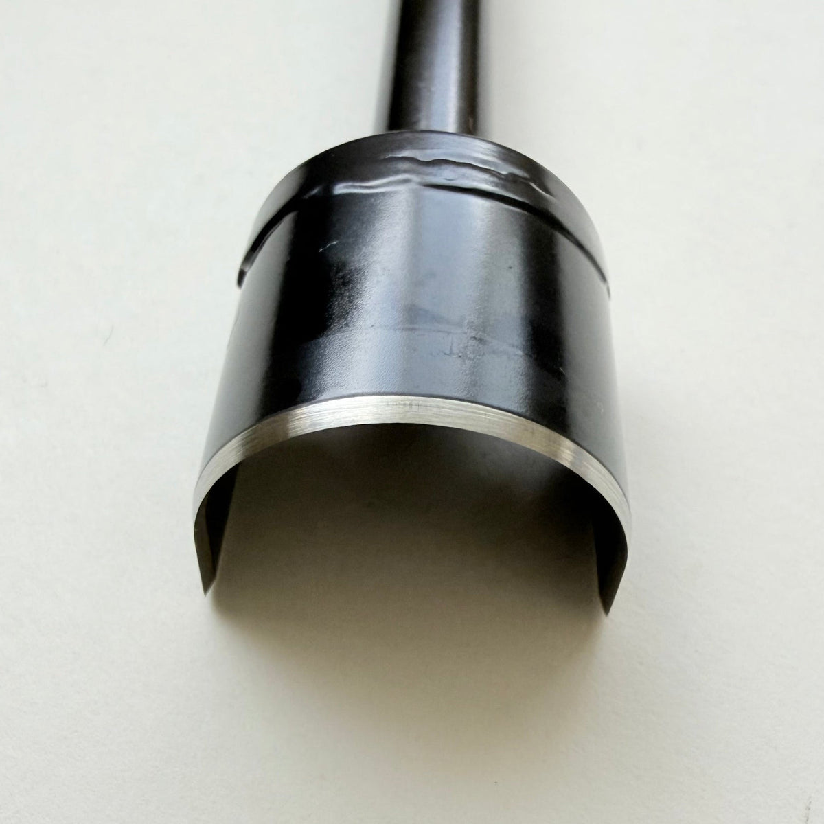 A black metal u shaped strap end punch with a silver steel cutting edge, shown on a plain light grey background.