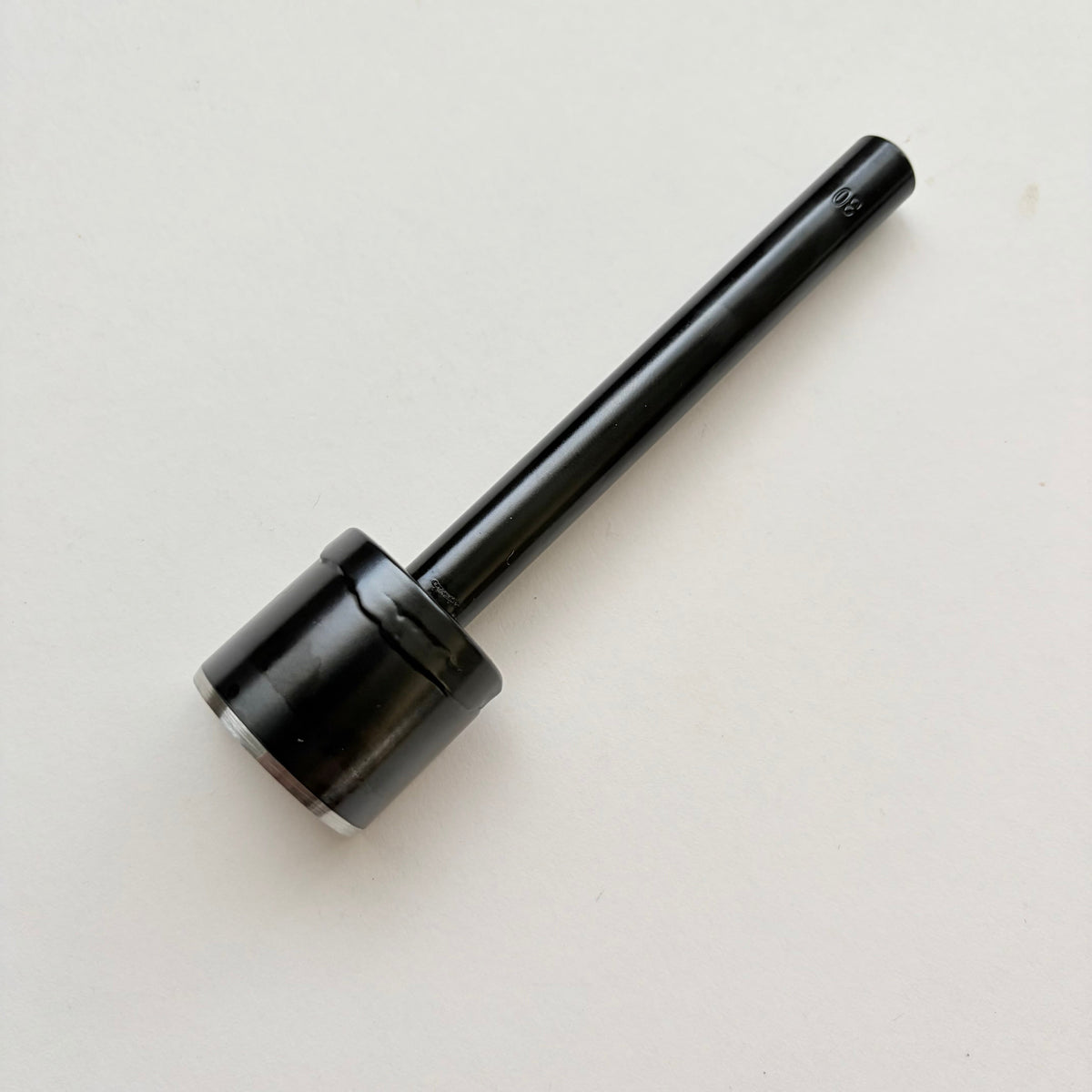 A black metal u shaped strap end punch with a silver steel cutting edge, shown on a plain light grey background.