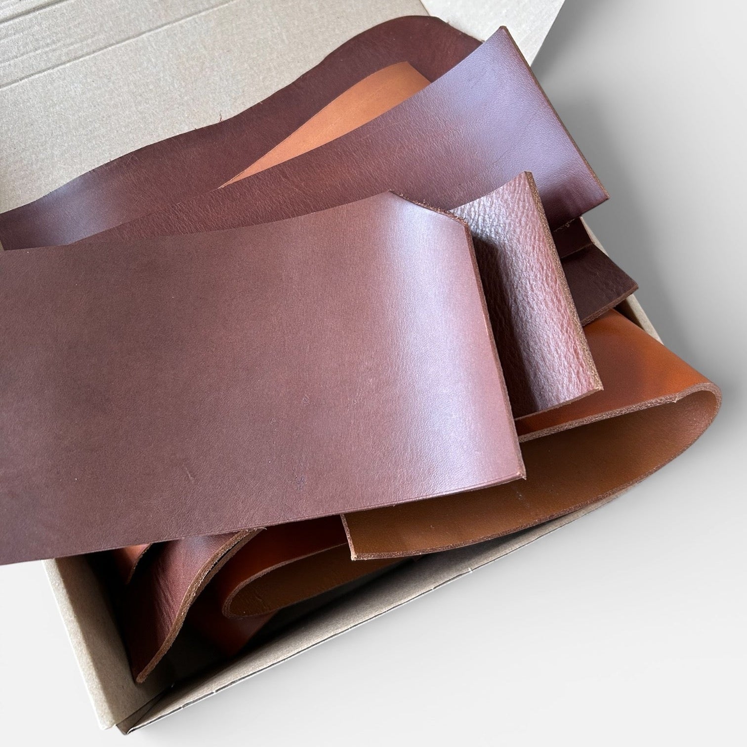 Box containing leather samples in various shades of brown on a light background